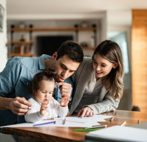 Young happy family having fun while coloring on the paper at home.